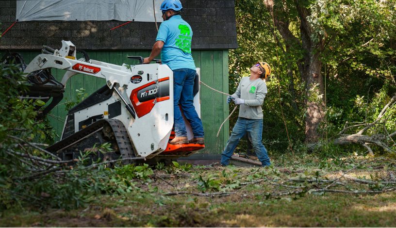 Green Bear Tree Service crew operating Bobcat MT100 mini track loader during residential lot clearing NC