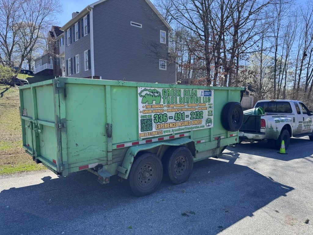 Green Bear Tree Service green dump trailer and work truck parked in residential neighborhood NC